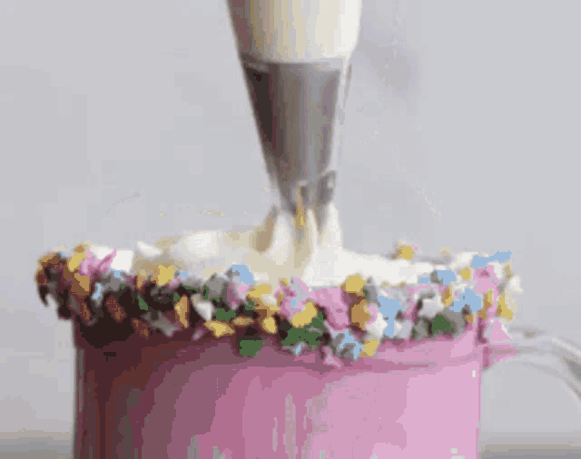 frosting is being piped into a cup with sprinkles