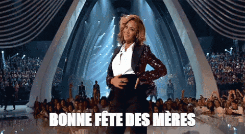 a pregnant woman is dancing on a stage in front of a crowd with the words bonne fete des meres above her