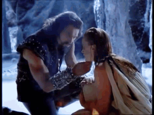 a man and a woman are kneeling next to each other in a cave .