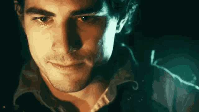 a close up of a man 's face with a green light behind him
