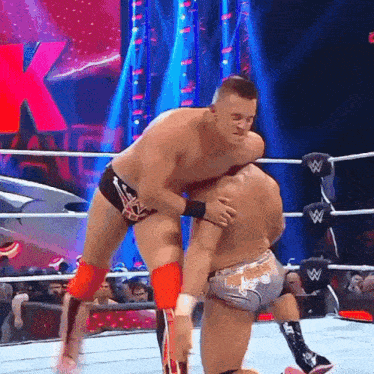two men are wrestling in a wrestling ring with a w logo on the ring