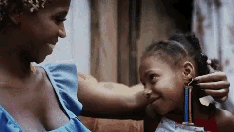 a woman is putting earrings in a little girl 's ear .