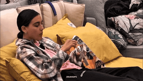 a woman in a plaid shirt is laying on a couch with a pillow that says ' andy ' on it
