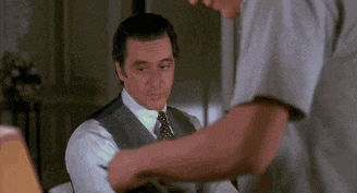 a man in a suit and tie is talking to another man in a white shirt