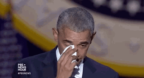 barack obama is crying while holding a tissue in his hand .