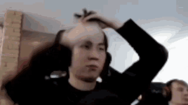 a man wearing headphones is holding his hair in his hands .