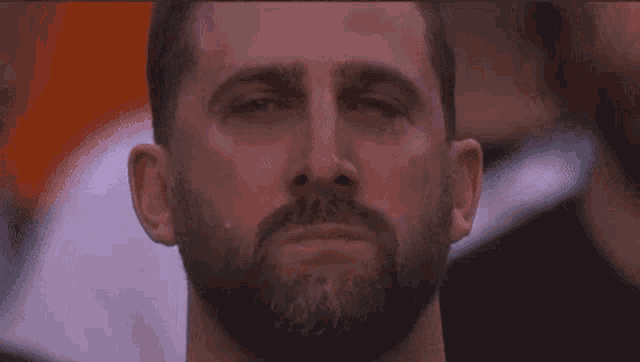 a man with a beard is crying with his eyes closed and a tear coming out of his nose .