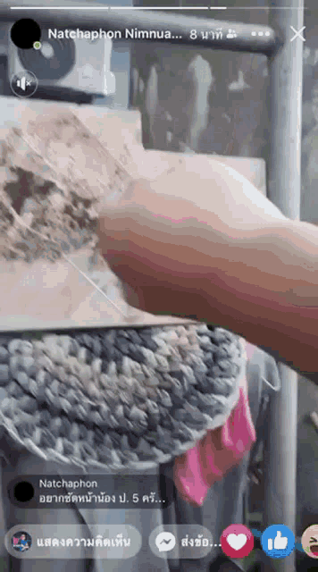 a person is holding a knife in front of a phone screen that says natchaphon nimnua on it