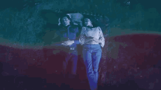 a man and a woman are laying in the grass with a blue and red background