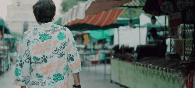 a man wearing a shirt that has a paw print on it walks down a street