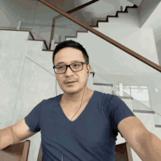 a man wearing glasses and a blue shirt is taking a selfie