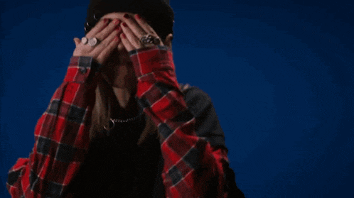 a woman wearing a plaid shirt and a black hat is making a funny face .