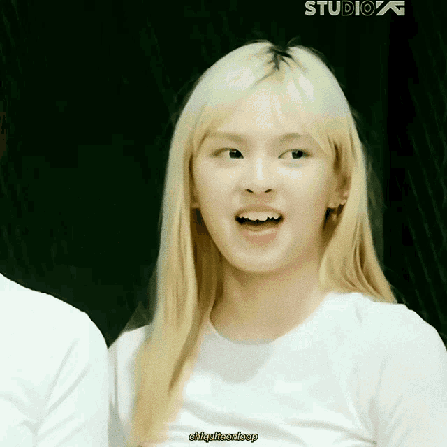 a girl with blonde hair is wearing a white t-shirt with the word studio on it
