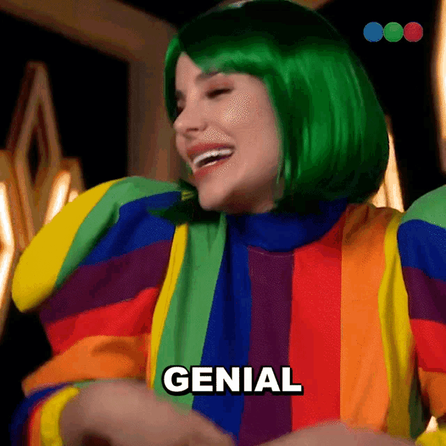 a woman wearing a green wig and a rainbow outfit says genial