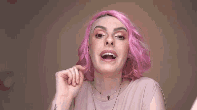 a woman with pink hair is smiling with the letter k above her