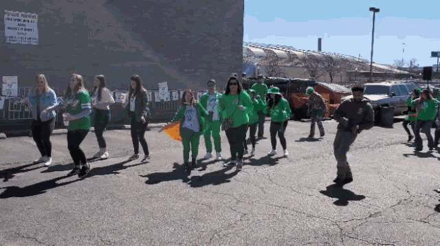 a group of people are marching down a street in front of a sign that says " no parking "