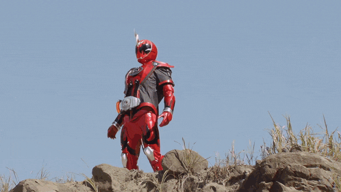 a man in a superhero costume stands on top of a rocky hillside