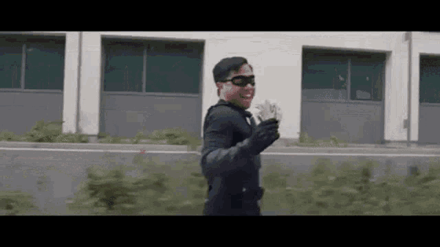 a man in a superhero costume is holding a bunch of money while walking down the street .