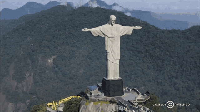 a statue of jesus on top of a mountain with a comedy central logo