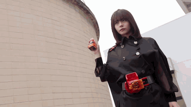 a woman in a black cape is holding a red object in her hand