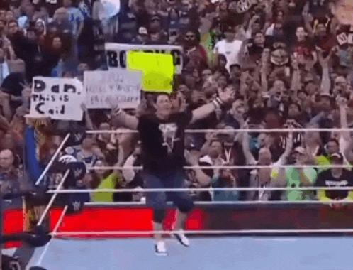 a man in a wrestling ring is holding a sign that says dan this is cool .