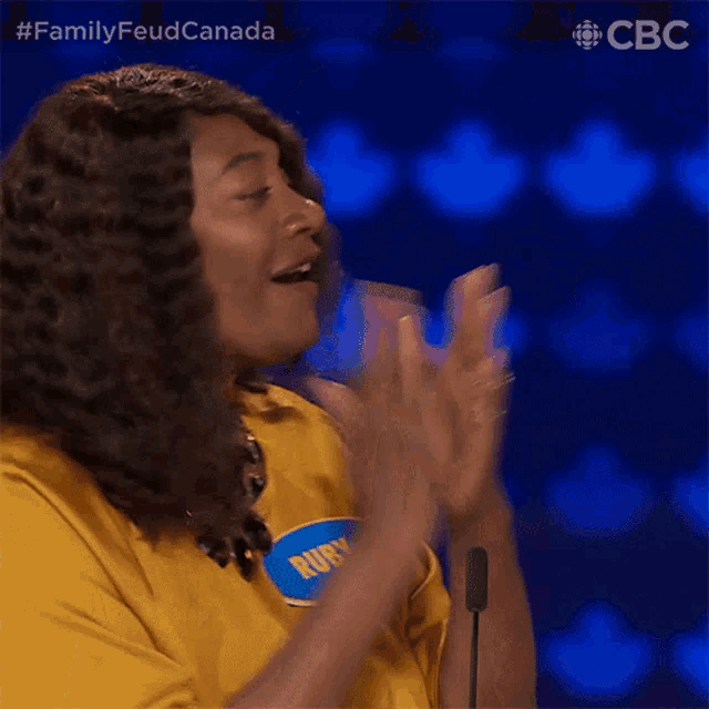 a woman wearing a yellow shirt with a name tag that says ruby is applauding .