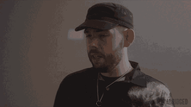 a man with a beard wearing a hat and a necklace with the word unabridged on the bottom right