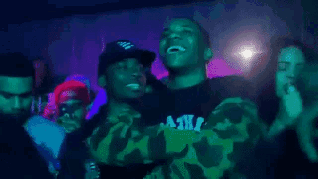 a group of men are dancing and laughing in a dark room in a club .