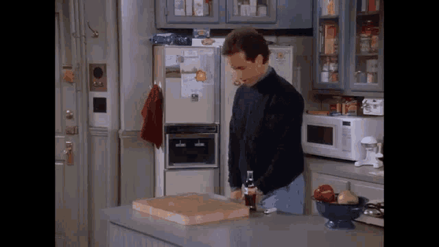 a man is standing in a kitchen with a cutting board and a bottle of coca cola .