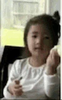 a little girl in a white shirt is sitting in a chair holding a pencil .