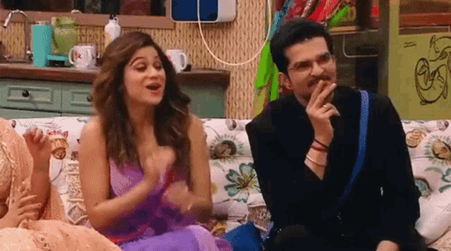 a man and a woman are sitting on a couch in a room .