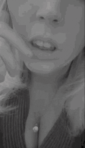 a black and white photo of a woman holding her finger to her lips .