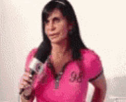 the woman is wearing a pink shirt and holding a microphone .