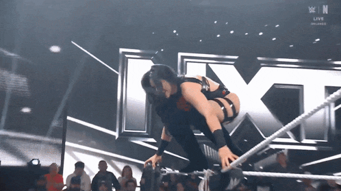 a wrestler is jumping over ropes in front of a large x