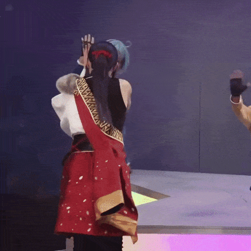 a man in a blue jacket and a woman in a red skirt are dancing on a stage