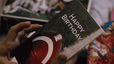 a person is holding a happy birthday card with a picture of a football .