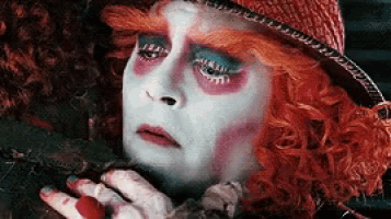 the mad hatter from alice in wonderland is wearing a red hat and a red wig .