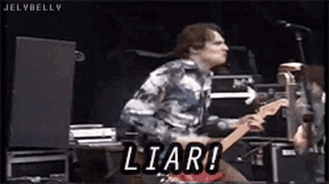 a man playing a guitar on a stage with the words liar written on the bottom