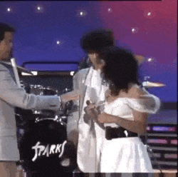 a man and a woman are hugging on a stage .