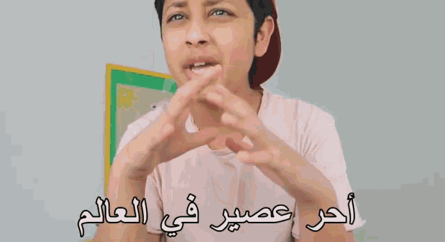 a boy in a pink shirt with arabic writing on the bottom