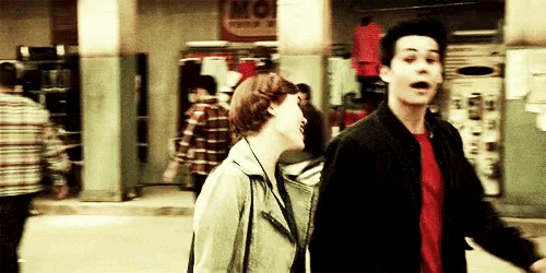 a man and a woman are walking down a street in front of a clothing store .