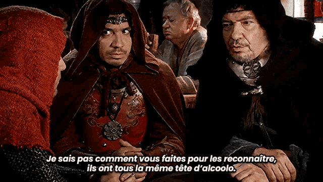 a man in a red cape is talking to another man in a black cape in a scene from a movie .