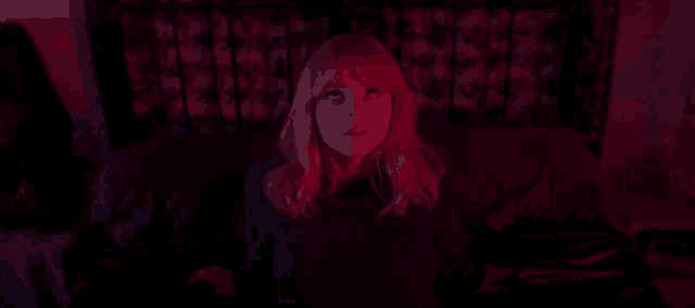 a woman is sitting on a bed with red lights behind her .