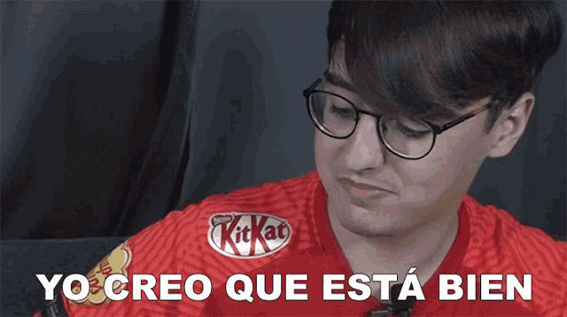 a man wearing glasses and a red kitkat shirt says yocreo que esta bien