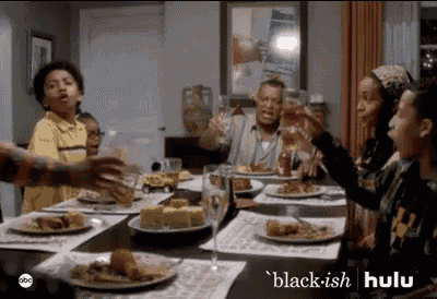 a group of people are sitting at a table with plates of food and drinks .