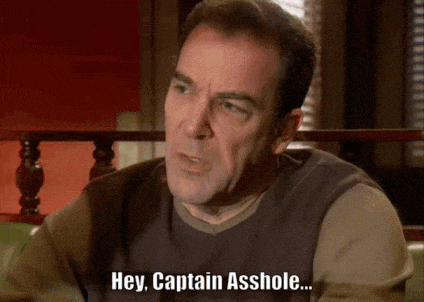 a man is sitting on a couch and says hey captain asshole
