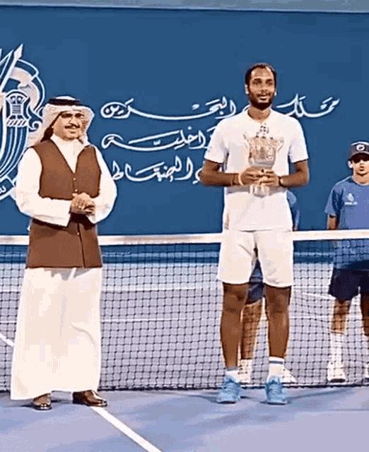 a man holding a trophy stands next to another man