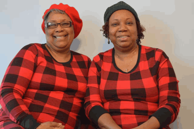 two women wearing red plaid shirts are sitting next to each other and smiling
