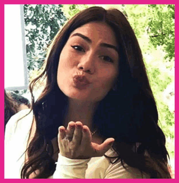 a woman is blowing a kiss with her hand in the air .