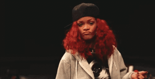 a woman with red hair is wearing a hat and a hoodie and giving the middle finger .